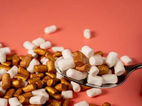 Mini marshmallows on a pink background. Marshmallow gold and white. Stock Photos