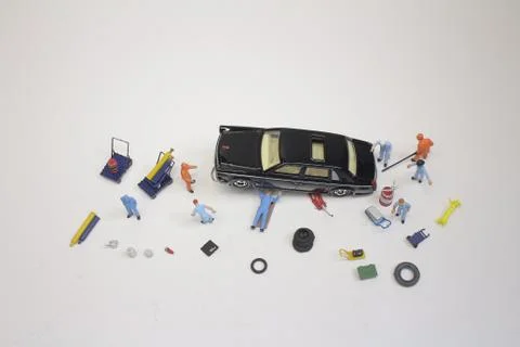 A mini mechanics replacing a punctured tyre of a car Fotos de archivo