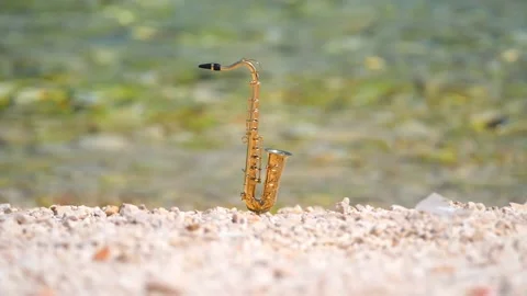Mini model of real alt tenor saxophone stands white small pebbles on seashore Stock Footage 139068694