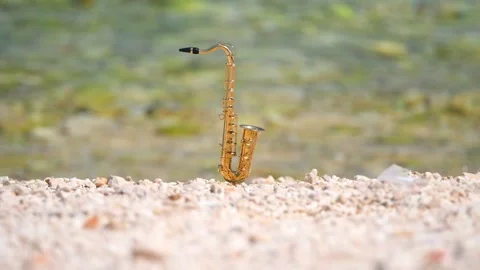 Mini model of real alt tenor saxophone stands white small pebbles on seashore Stock Footage 139069144