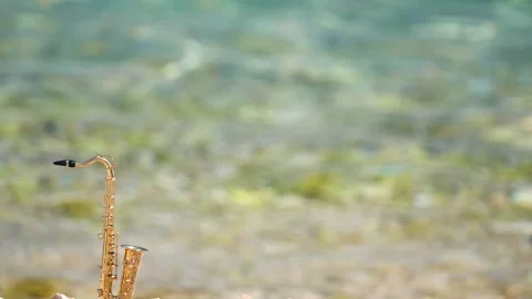 Mini model of real alt tenor saxophone stands white small pebbles on seashore Stock Footage 139073163
