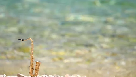 Mini model of real alt tenor saxophone stands white small pebbles on seashore Stock Footage 139073325