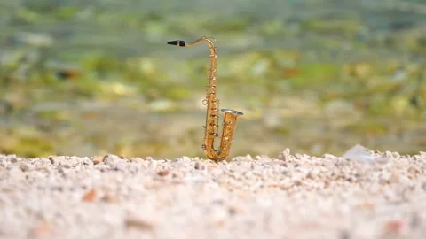 Mini model of real alt tenor saxophone stands white small pebbles on seashore Stock Footage 139073537