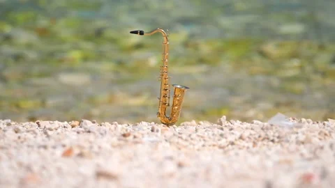 Mini model of real alt tenor saxophone stands white small pebbles on seashore Stock Footage 139073600