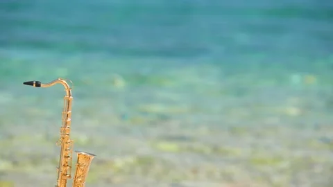 Mini model of real alt tenor saxophone stands white small pebbles on seashore Stock Footage 147919380