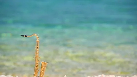 Mini model of real alt tenor saxophone stands white small pebbles on seashore Stock Footage 147922032