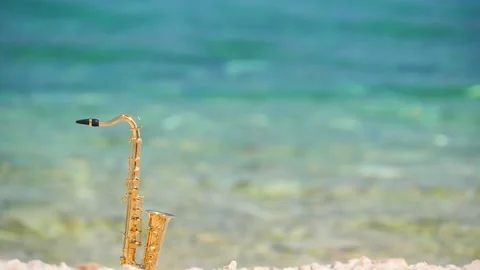 Mini model of real alt tenor saxophone stands white small pebbles on seashore Stock Footage 147922250