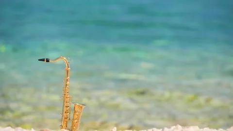 Mini model of real alt tenor saxophone stands white small pebbles on seashore Stock Footage 147922736