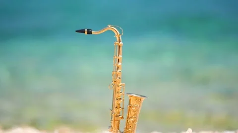 Mini model of real alt tenor saxophone stands white small pebbles on seashore Stock Footage 147924015