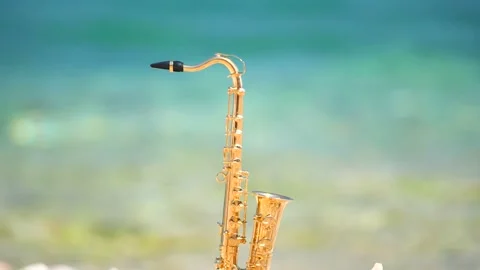 Mini model of real alt tenor saxophone stands white small pebbles on seashore Stock Footage 147924684