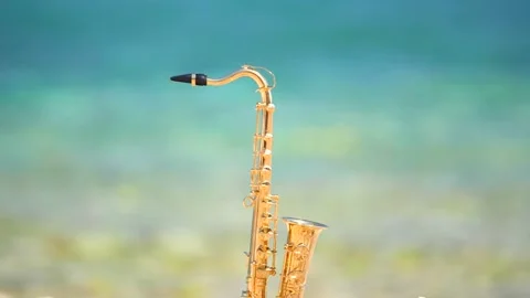 Mini model of real alt tenor saxophone stands white small pebbles on seashore Stock Footage 147924771