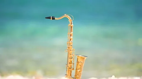 Mini model of real alt tenor saxophone stands white small pebbles on seashore Stock Footage 147925454