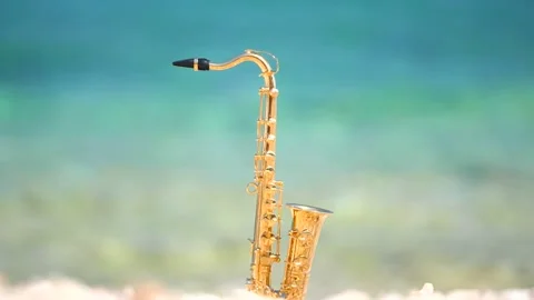 Mini model of real alt tenor saxophone stands white small pebbles on seashore Stock Footage 147925663