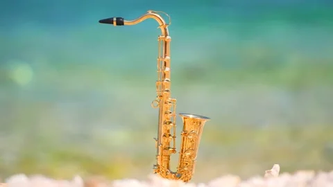 Mini model of real alt tenor saxophone stands white small pebbles on seashore Stock Footage 147925961