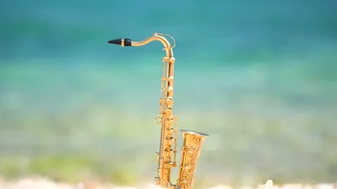 Mini model of real alt tenor saxophone stands white small pebbles on seashore Stock Footage 147926269