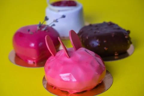 Mini mousse pastry dessert covered with mirror glaze on yellow background. Mo Stock Photos