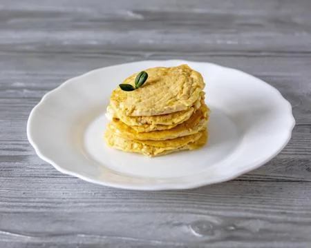 Mini omelets on a white plate on a gray wooden table. Stock Photos