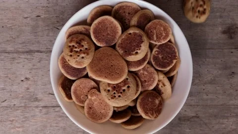 Mini pancakes falling in bowl in slow motion, top view. Tiny pancake cereal 動画素材 131106702