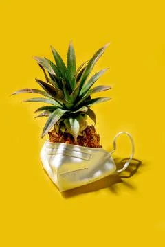 Mini pineapple in mask on a solid yellow background Foto stock