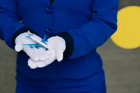 The mini plane's layout is in the hands of a flight attendant in white gloves Stock Photos