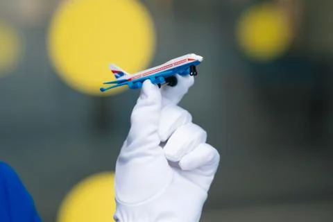 The mini plane's layout is in the hands of a flight attendant in white gloves Stock Photos