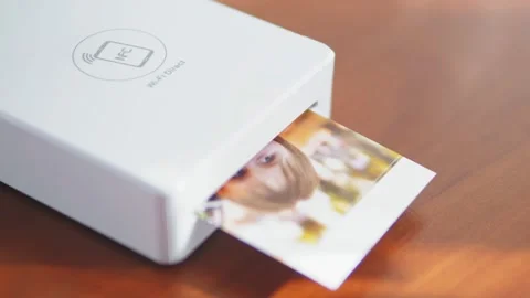 The mini printer prints out a photo of a small child. Wireless mini printer for Stock Footage 218396036