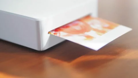 The mini printer prints out a photo of a small child. Wireless mini printer for Stock Footage 218450825