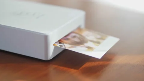 The mini printer prints out a photo of a small child. Wireless mini printer for Stock Footage 218624547