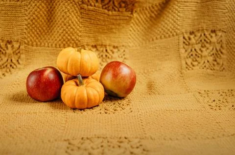 Mini pumpkins and apples on warm yellow blanket. Stock Photos