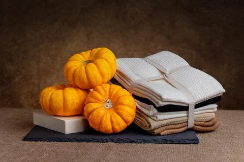 Mini pumpkins beside folded waffle-weave textiles on burlap Stock Photos