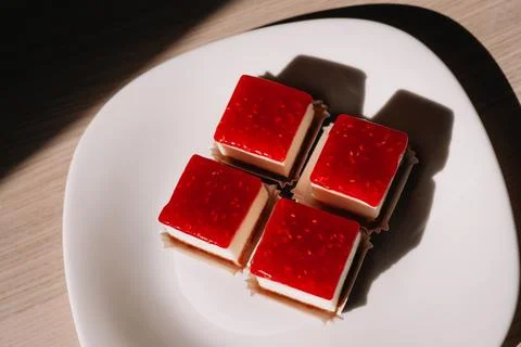 Mini raspberry cheesecakes on white plate with dramatic shadows, top view 스톡 사진