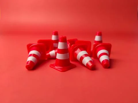 Mini red plastic cones scattered on a red background Stock Photos