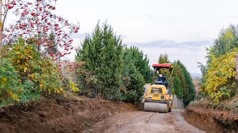 Mini road roller leveling a soil with gravel substructure for a new walkway i Stock Photos