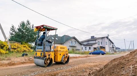 Mini road roller leveling a soil with gravel substructure for a new walkway i Stock Photos