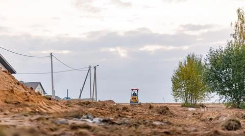 Mini road roller leveling a soil with gravel substructure for a new walkway i Stock Photos