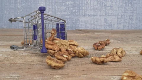 A Mini Shopping Cart Filled with Assorted Nuts on a Wooden Surface Ready for 動画素材 288353875