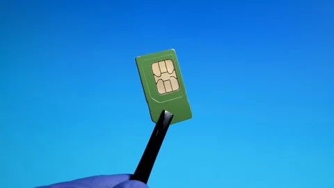 Mini sim card close-up on blue background in tweezers of technical workers Stock Footage 129981872
