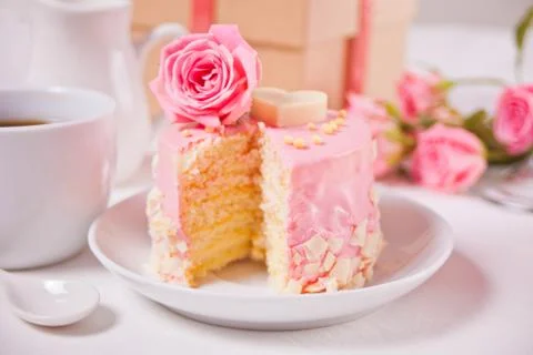 Mini small cake with pink glaze, beautiful roses, cup of coffee, gift box on  Stock Photos
