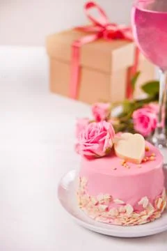 Mini small cake with pink glaze, beautiful roses, cup of coffee, gift box on  Stock Photos
