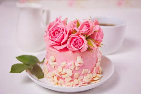 Mini small cake with pink glaze, beautiful roses, cup of coffee, gift box on  Stock Photos