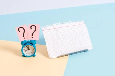 Mini small size alarm clock beside a Paper sheet placed tilted. Notepaper on the Stock Photos