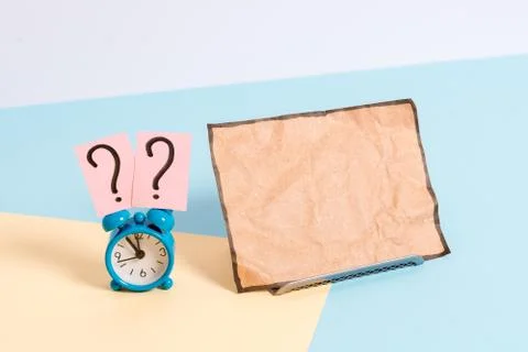 Mini small size alarm clock beside a Paper sheet placed tilted. Notepaper on the Stock Photos