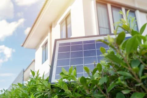 Mini solar cell panel setting on top of tree wall over house and blue sky. .. Stock Photos