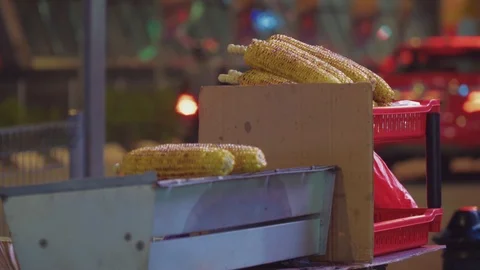 Mini stall selling fresh baked corn on street with crowd of people at downtown Stock Footage 107345847