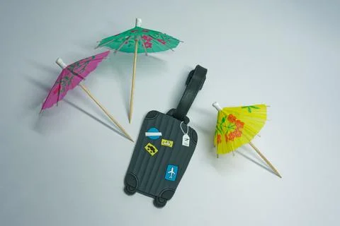Mini Suitcase Key chain and Cocktail Umbrellas on White Background Stock Photos