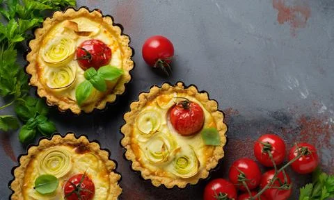 Mini tart with baked Leeks, cherry tomatoes and cream sauce on a gray concret Stock Photos