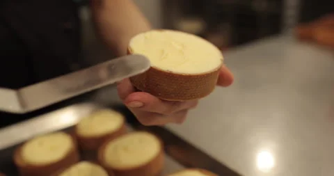 A mini-tart in the hands of a pastry chef at the time of spreading the cream. Stock Footage 251952091