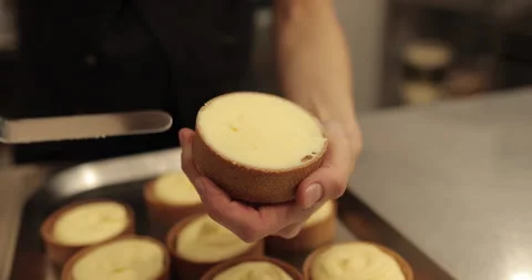A mini-tart in the hands of a pastry chef at the time of spreading the cream. Stock Footage 251952389