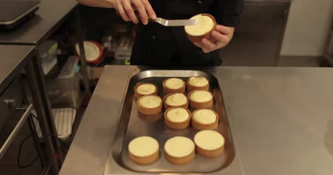 A mini-tart in the hands of a pastry chef at the time of spreading the cream. Stock Footage 251952575