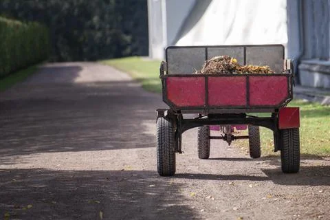 Mini tractor loaded with fallen leaves on a rustic country road during autumn Stock Photos
